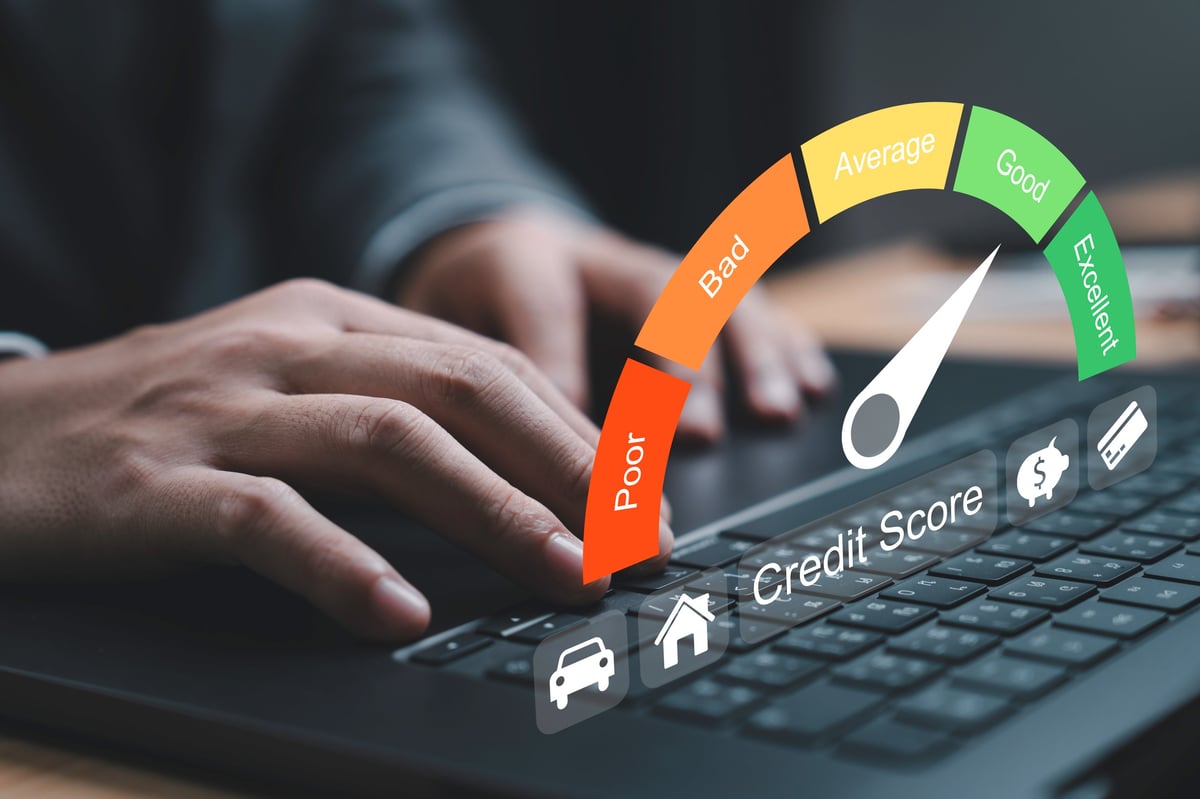 A laptop displaying a credit score gauge indicating ranges from poor to excellent